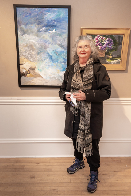Karen Berman-Mulligan stands besides her entry at the Experimental Art Group's April, 2023 show at the Charles Fine Arts Gallery in Gloucester
